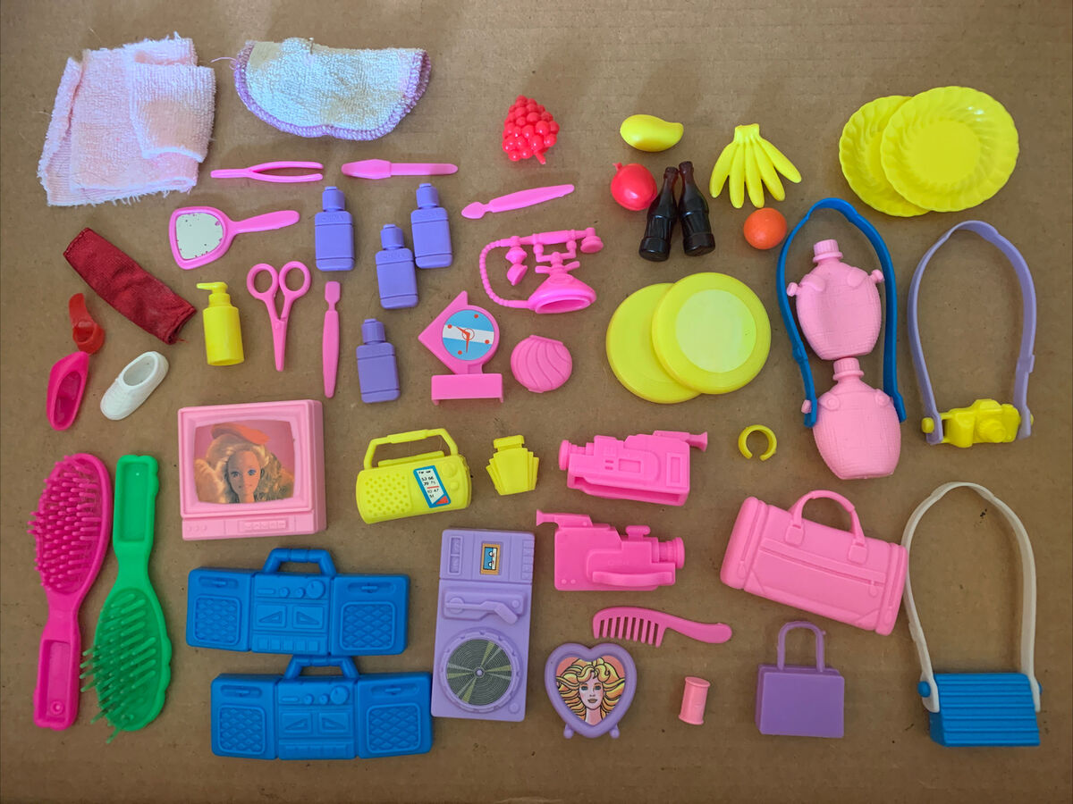 Barbie accessories from the 1980s, including neon-colored hairbrushes, plates, purse, cameras, scissors, shoes, a television set, etc.